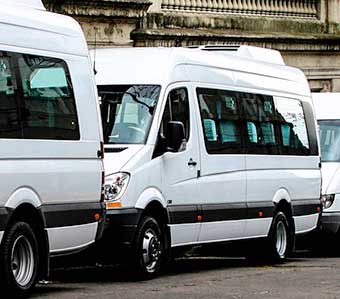 Combis blancas estacionadas listas para traslados corporativos, servicio de alquiler con chofer para empresas.